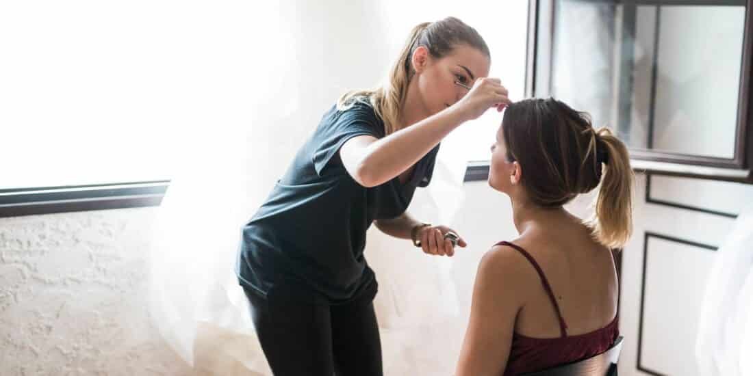 En train de maquiller Laetitia lors des préparatifs de son mariage, capturé par Deborah Milasseau, avec les reflets chaleureux du soleil.